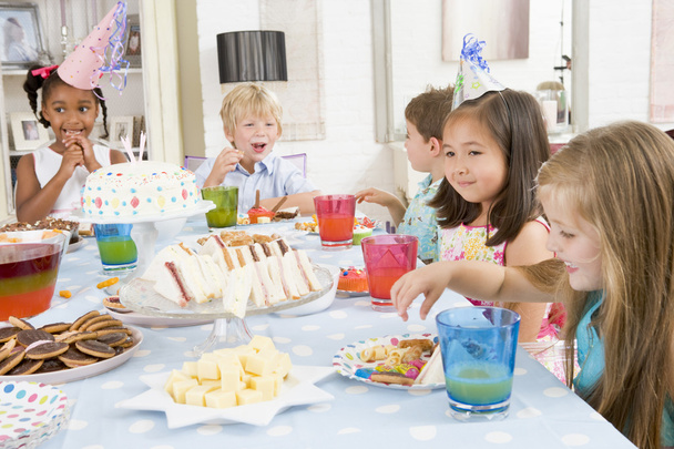 Young children at party sitting at table with food smiling - 写真・画像