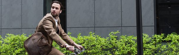 bearded businessman in earphones riding bicycle outside, banner - 写真・画像