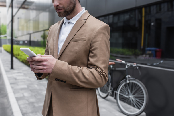 cropped view of bearded businessman using smartphone outside  - Foto, immagini