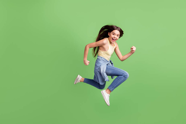 Full length body size view of pretty energetic cheerful girl jumping running isolated over bright green color background - Fotó, kép
