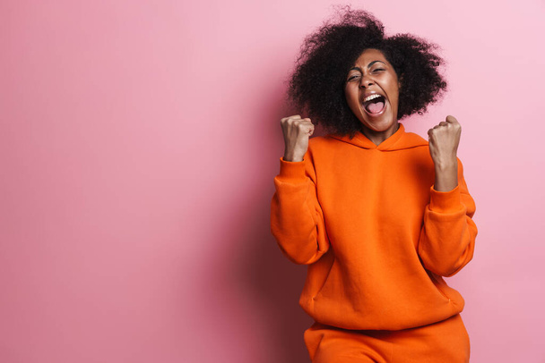 Delighted african american girl screaming and making winner gesture isolated over pink background - Foto, Bild