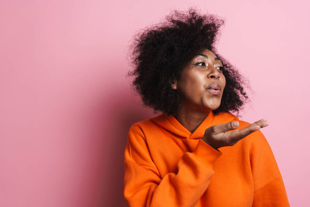 Happy african american woman blowing air kiss aside isolated over pink background - Photo, Image