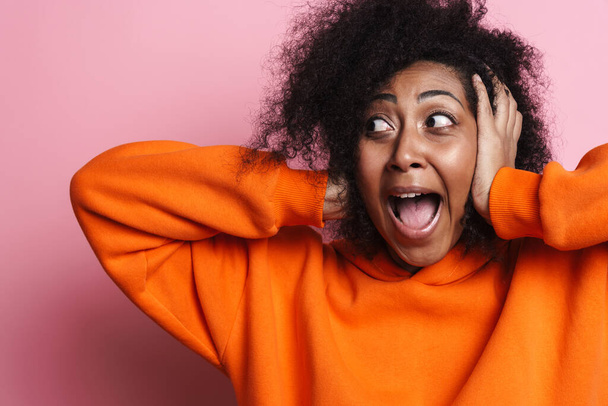 Ενθουσιασμένη Αφροαμερικανή που καλύπτει τα αυτιά της και ουρλιάζει απομονωμένη σε ροζ φόντο. - Φωτογραφία, εικόνα