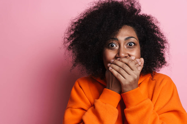 Excited african american woman covering her mouth and looking at camera isolated over pink background - Φωτογραφία, εικόνα