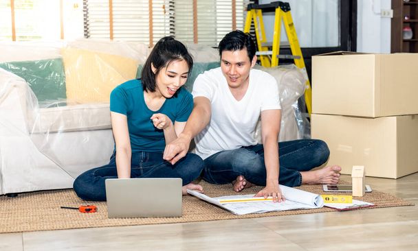 Asian couple, Husband and attractive wife looking at computer notebook and discuss about renovating the old house to be new home, to people, Real estate and renovation concept. - Photo, Image