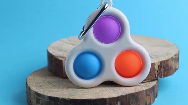 人気のおもちゃのポップのレビューシンプルなディンプルは青い背景に木製のスタンドにあります - 映像、動画