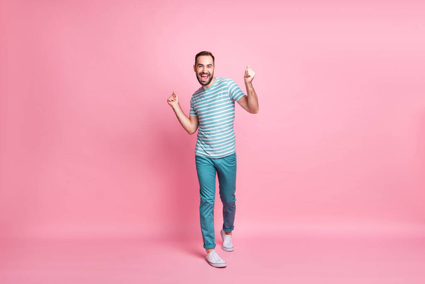 Full length body size view of nice attractive playful cheerful guy walking having fun isolated over pink pastel color background - 写真・画像