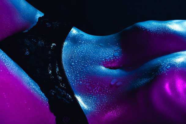Sexy cuerpo de chica con una barriga delgada con gotas de sudor y agua en la piel de cerca. Figura de mujer hermosa - Foto, Imagen