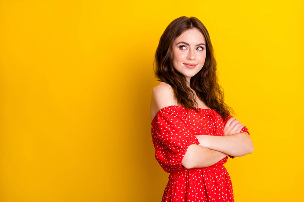 Photo portrait of pretty lady with crossed hands smiling in red dress looking blank space isolated vibrant yellow color background - Photo, Image