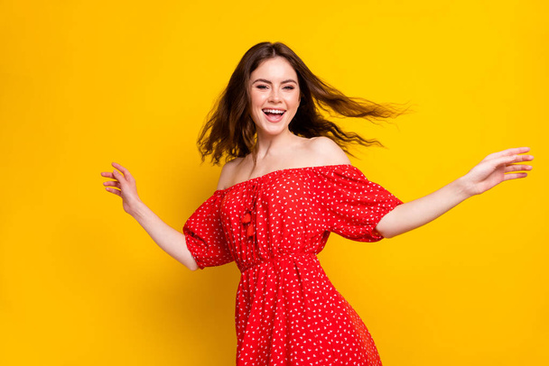 Photo portrait of cheerful happy girl laughing in printed dress dancing in summer isolated vibrant yellow color background - Foto, Imagem