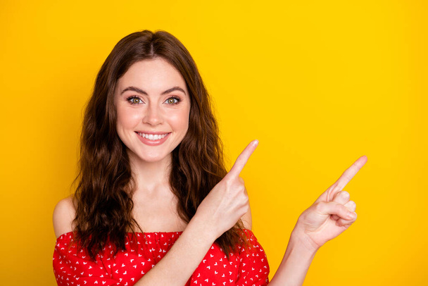 Photo portrait of nice girl in red shirt showing fingers empty space recommending isolated vivid yellow color background - Zdjęcie, obraz