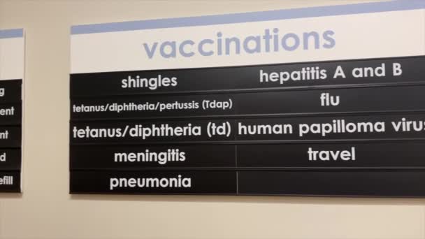 Allekirjoitus lukee luettelon saatavilla olevista rokotuksista sairaalan odotushuoneessa. - Materiaali, video