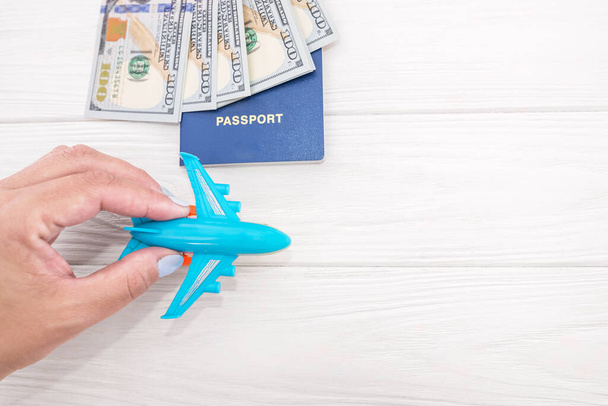 Photo d'une vue de dessus d'un avion en main, passeports avec des dollars sur un fond en bois avec espace de copie. Concept de voyage. - Photo, image