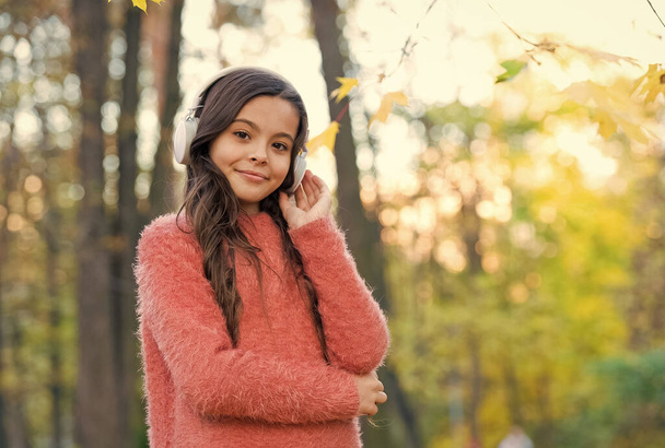Confident in style. fall is a time for study. back to school. concept of online education. child in sweater enjoy listening ebook. new technology. girl in earphones. kid listen music in autumn park - Foto, imagen