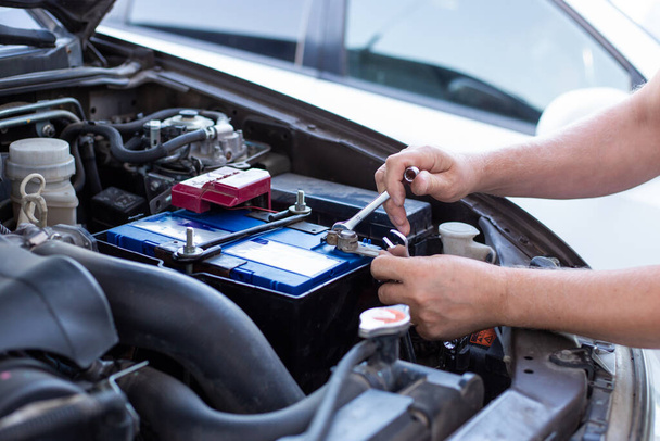 a man tightens with a wrench bolts for fastening a new battery, installing spare parts for a car - Foto, imagen