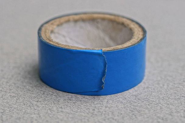 una madeja de cinta plástica azul yace sobre una mesa gris - Foto, imagen