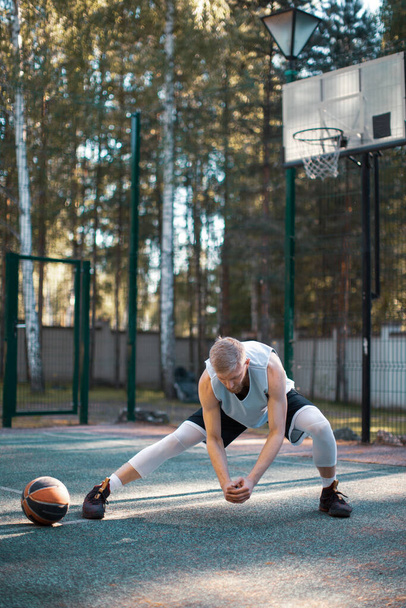 Professional male american basketball player training, warming up on court outdoors in summer. Energetic workout - 写真・画像