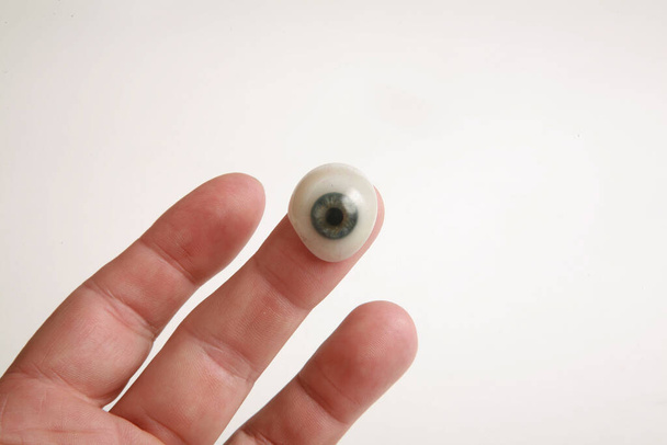 eine menschliche Hand hält ein echtes Glasauge. antike prothetische Auge. Glasauge. Fake-Eye. menschliches Auge. medizinisches Glasauge. ein antikes menschliches Glasauge. - Foto, Bild