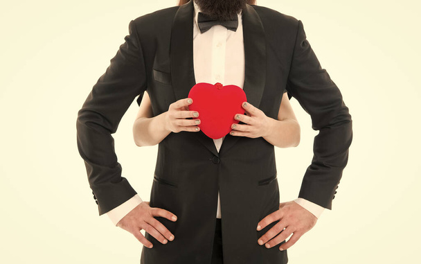 You are my heart and my soul. Female hands hold heart red toy symbol of love in front of man in tuxedo. Take this heart. Donation and sacrifice. Strong feeling. Trust and support. Heart romantic sign - Fotoğraf, Görsel
