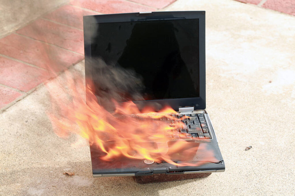 A genuine Lap Top Computer completely engulfed in flames of fire. Computer damage due to a person typing so fast they burned up the internet or were writing something so HOT it literally caught fire. Laptop burning fire hazard. Computer Fire.   - Photo, Image