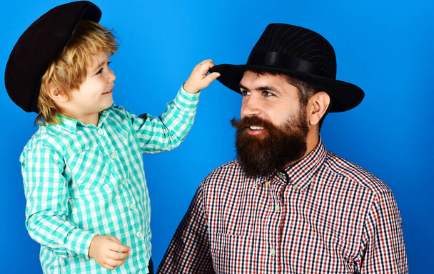 Fathers day. Happy dad with son in checkered shirts and fashionable hats. Parenthood concept. - Photo, Image
