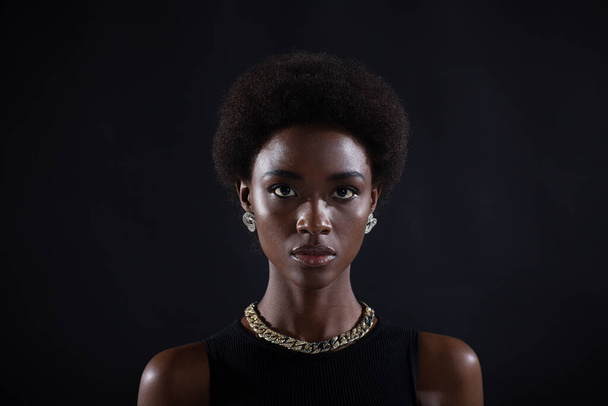 Nahaufnahme Porträt einer afrikanisch-amerikanischen Frau mit Afro-Frisur auf schwarzem Studiohintergrund - Foto, Bild