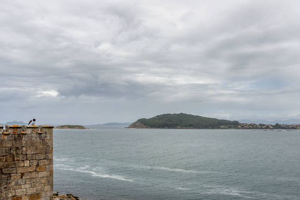 Les gens observent l'horizon océanique par une journée nuageuse depuis le haut d'un mur - Photo, image
