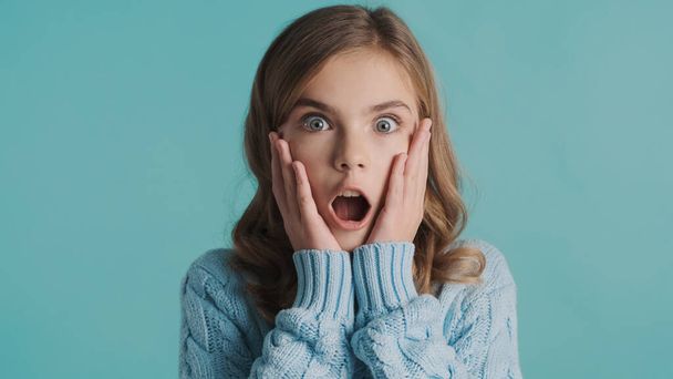 Portrait of attractive blond teenager girl looking surprised over blue background. Wow expression. I can not belive emotion - Foto, imagen