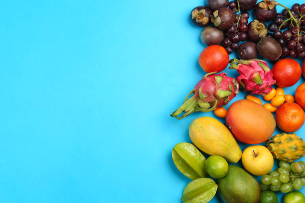 Assortment of fresh exotic fruits on light blue background, flat lay. Space for text - Fotó, kép