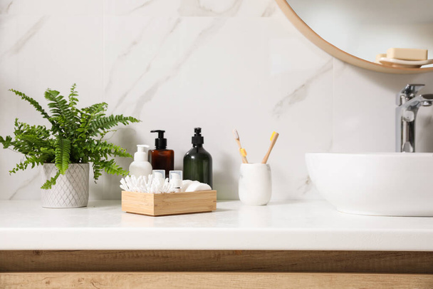 Beautiful green fern and toiletries on countertop in bathroom - Foto, imagen