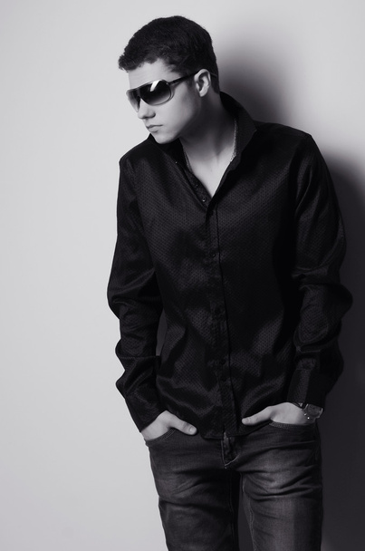 Fashion portrait of young man in black shirt poses over wall - Foto, Imagem