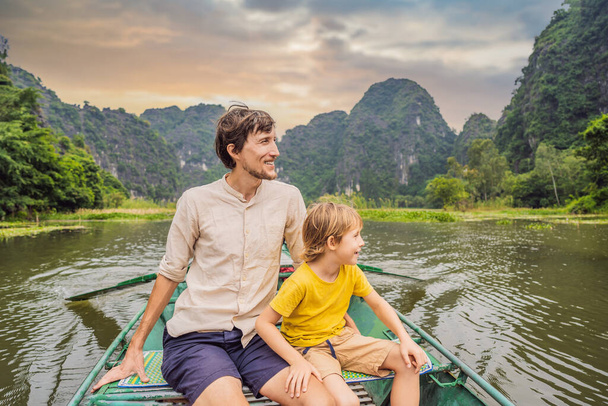 Dad and son tourists in boat on the lake Tam Coc, Ninh Binh, Viet nam. Its is UNESCO World Heritage Site, renowned for its boat cave tours. Its Halong Bay on land of Vietnam. Vietnam reopens borders - Фото, зображення