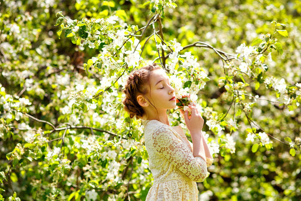 Дівчинка мріє про яблучний сад, свіжу ніжність весняної дівчини у квітах. Дитина стоїть з закритими очима і насолоджується ароматом квітучого саду
. - Фото, зображення