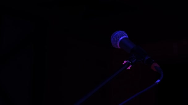 Lähikuva Professional mikrofoni tyhjällä pimeällä lavalla mustalla taustalla. - Materiaali, video