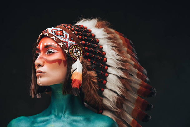 Woman chief with indian headwear against dark background - Photo, Image