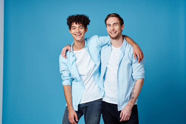 Typ mit lockigem Haar in Hemd und T-Shirt auf blauem Hintergrund und einem jungen Mann mit Freunden - Foto, Bild