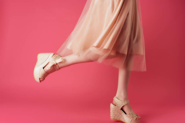 female legs in beige shoes posing close-up pink background - 写真・画像
