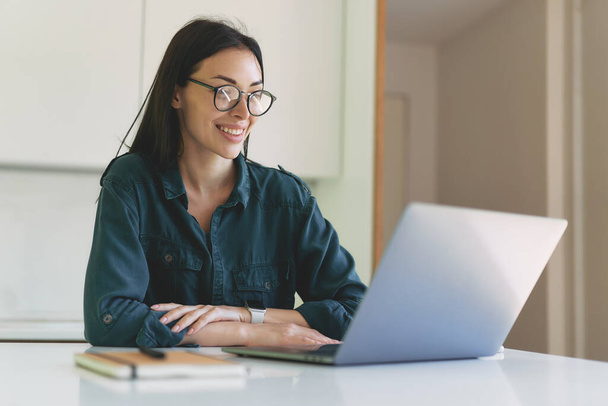 Smiling business woman working from home with laptop and notebook - Photo, Image