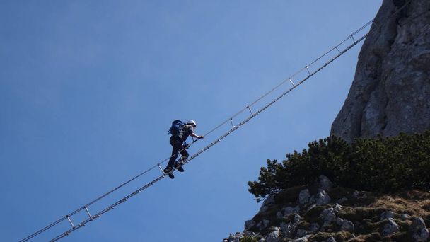 Via ferrata Donnerkogel Intersport klettersteig nelle Alpi austriache, Scalatore su una scala lunga 40 metri tra due montagne rocciose - Foto, immagini