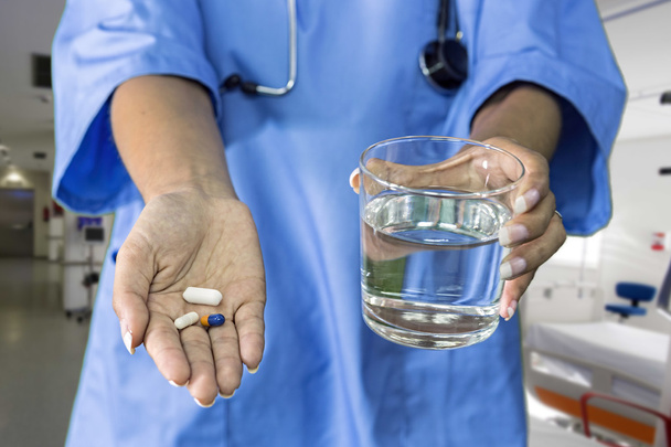 Imagen de las manos del médico dando píldoras blancas y vaso de agua - Foto, imagen