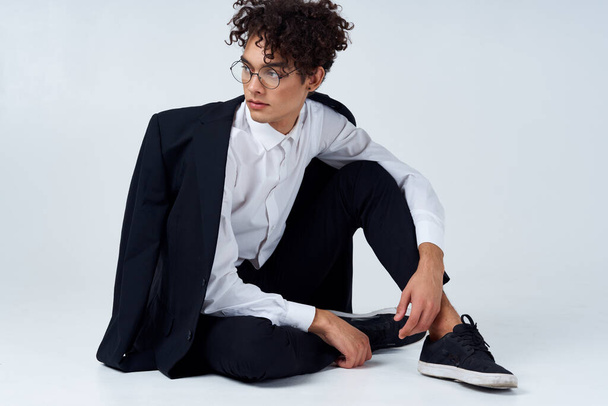 handsome guy in a jacket and shirt and glasses In a bright room photo studio model hairstyle curly hair - Foto, Imagen