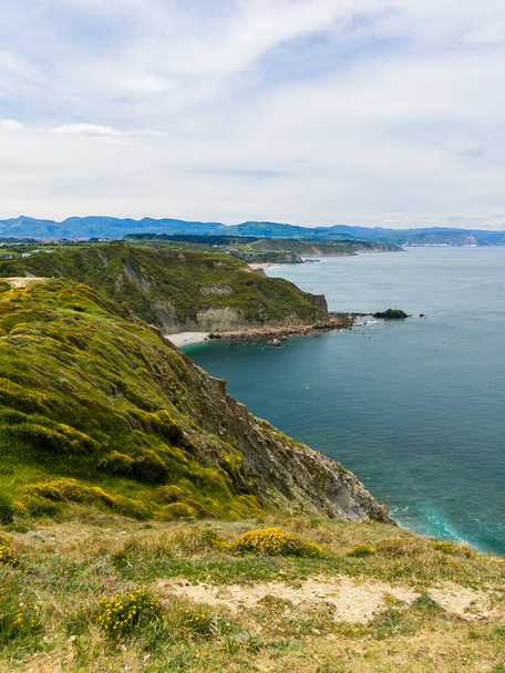 A natural view of grass field cliff near a coast under a cloudy sky - Photo, Image