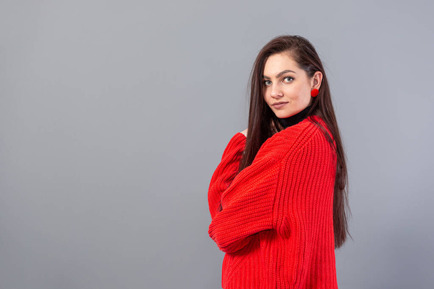 young emotional teenage woman with glasses dressed in a red sweater posing on a gray background - Foto, afbeelding