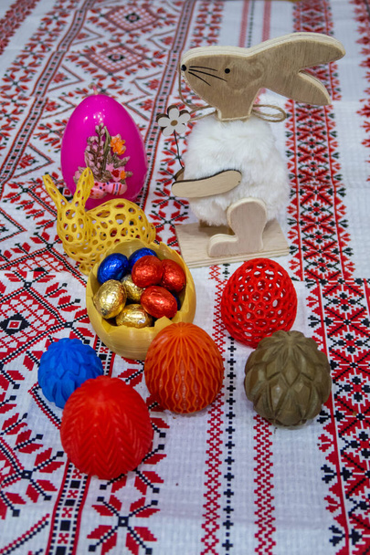 Funny decorative Easter rabbits, colorful and sweet eggs on the ornamented tablecloth - Foto, Bild