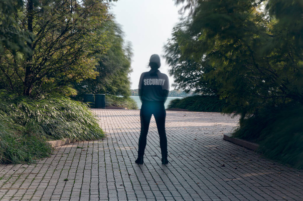 A closeup shot of a female security guard in uniform and watching over the park area - Zdjęcie, obraz