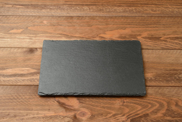 Empty blackboard dish on brown wooden table, top view - Foto, Imagen