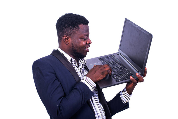 joven hombre de negocios vistiendo un traje elegante y trabajando en el portátil mientras sonríe. - Foto, imagen