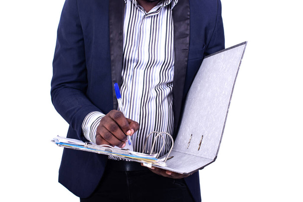 νεαρός σοβαρός επιχειρηματίας φορώντας ένα κομψό κοστούμι και γράφοντας με ένα στυλό στο ντουλάπι αρχειοθέτησης. - Φωτογραφία, εικόνα