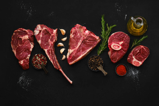Overhead composition with raw prime beef cuts - porter house, cowboy steak, ossobuco, ribeye and tri-tip roast - Foto, Imagen