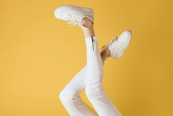 umgekehrte Beine in weißen Turnschuhen Mode modernen Stils gelb Hintergrund - Foto, Bild